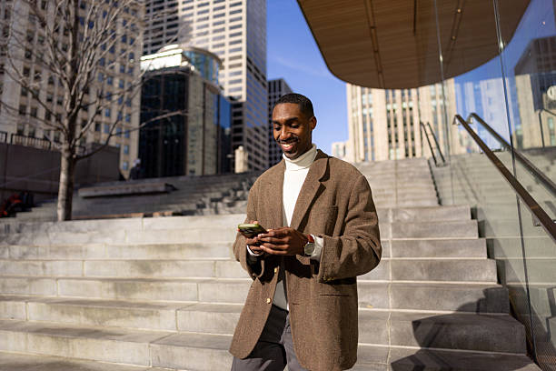 istock Young businessman using phone while walking down the stairs in the city 2229010486