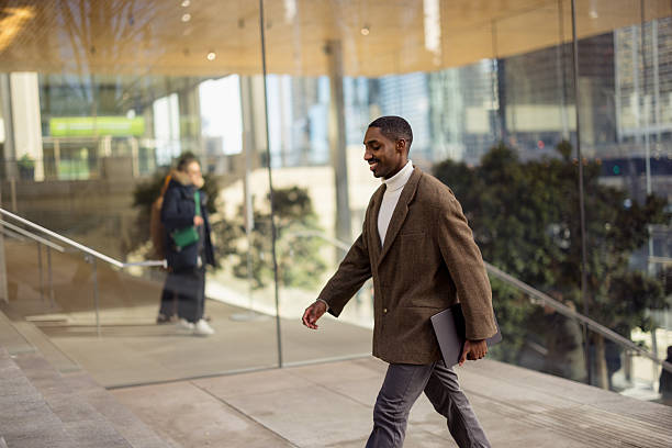 istock Smiling businessman walking outside modern office building 2229010511