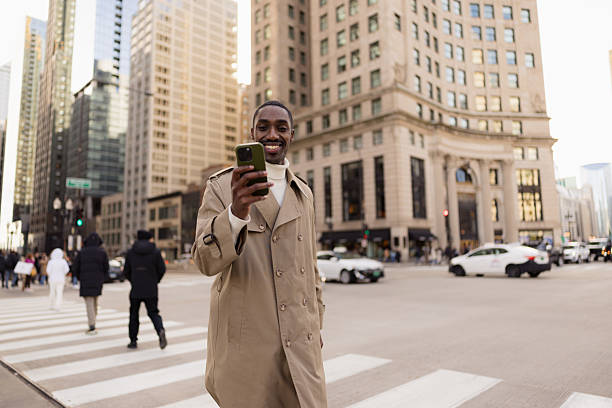 istock Young businessman using smartphone while crossing the street in chicago 2229010560