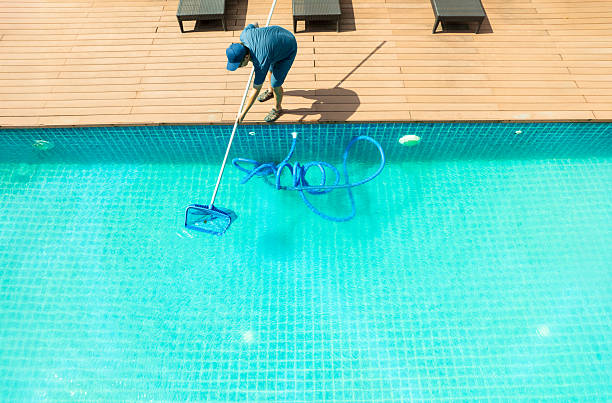 istock Pool maintenance with scoop net  and automatic robot cleaner. 2229013515
