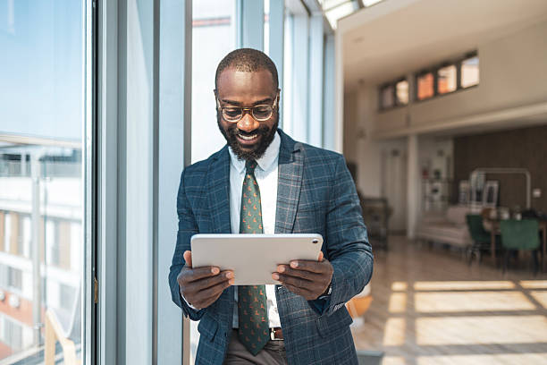 istock Smiling businessman holding a tablet in a bright modern office environment 2229013725