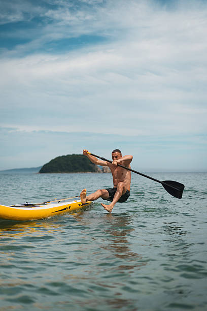 istock Young man falling off paddleboard during energetic summer adventure in clear sea. Action-packed outdoor moment full of fun, splash, water, sun and freedom. 2229014095