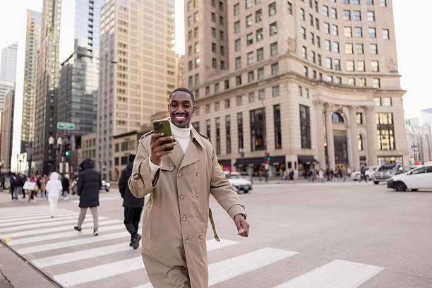istock Smiling businessman using smartphone while crossing city street 2229016149