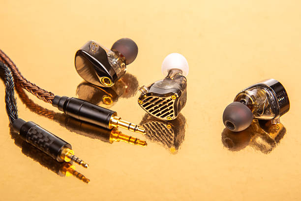 istock Three earbuds with braided cables and 3.5mm plugs on a gold surface, great for showcasing audio accessories and tech equipment. 2229020777