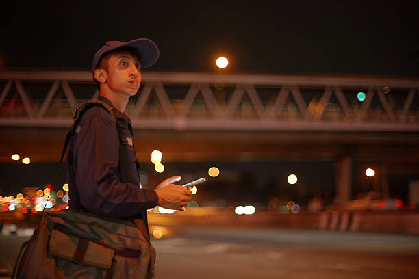 Asian man technician booking a taxi via mobile phone and waiting for the taxi.