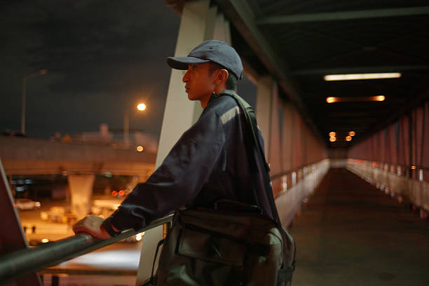 A blue collar worker stands outdoors at night deep in thought about his life