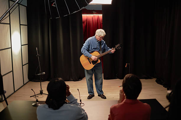 istock Senior Caucasian Man Performing Guitar Solo on Stage during Talent Competition 2229021414