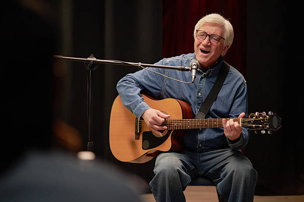 istock Senior Man Singing and Playing Guitar on Stage during Talent Competition 2229021454