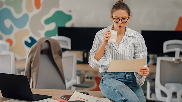 istock Businesswoman drinking coffee and reading documents in modern office 2229021531