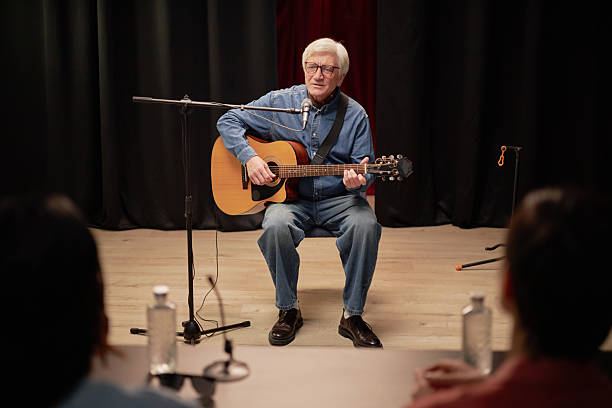 istock Senior Man Showcasing Musical Talent with Guitar before Judges 2229022747