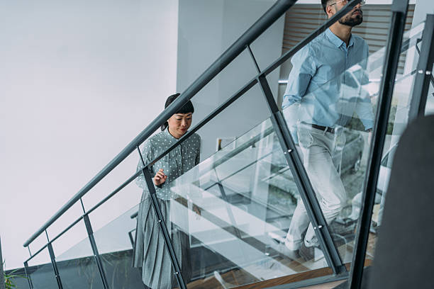 istock Business persons walking up on stairs in modern office. 2229024500