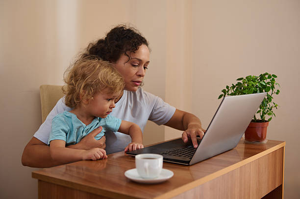 istock Mother Multitasking While Working on a Laptop at Home with Her Child 2229024944