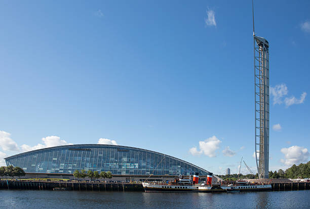 PS Waverley (launched 1946), the world's last ocean-going paddle steamer, outside the Science Centre on Pacific Quay on the River Clyde in central Glasgow, Scotland. The currently-closed Science Centre Tower can also be seen. Passengers are queueing up to board the ship.