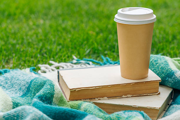 Picnic on a lawn with books and coffee on a sunny day