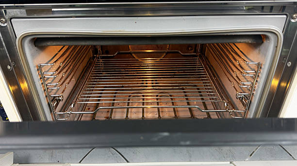 istock Empty electric oven with open door and metal grill racks, clean interior illuminated with warm light, ready for baking, cooking, or kitchen appliance demonstration 2229033032