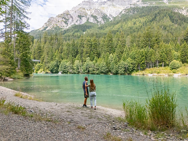 istock Couple Walking by Mountain Lake Shore 2229037290