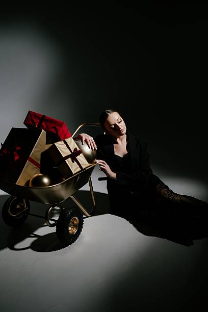 istock Pensive Woman by Gift Cart with Presents in Dark Setting 2229041605