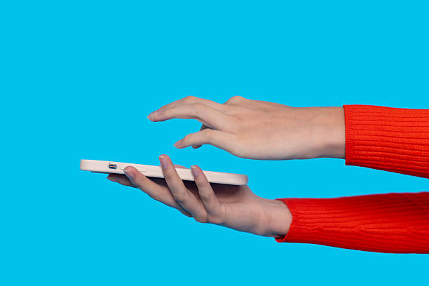 A person is interacting with a smartphone using one hand, showcasing the contrast of a bright red sweater against a striking blue background, suggesting a casual setting.