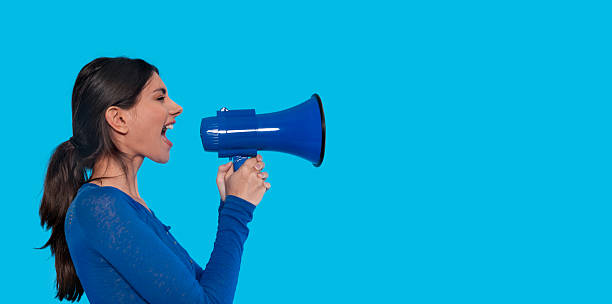 istock Woman shouting into a blue megaphone against a bright turquoise background during a public speaking event 2229042047