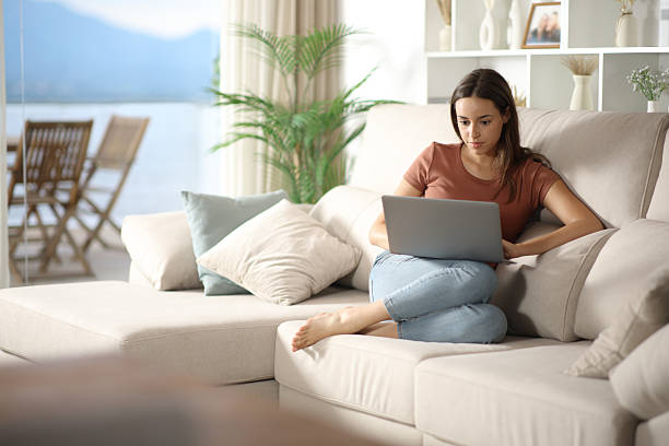 istock Woman using personal computer sitting on a sofa at home 2229042258