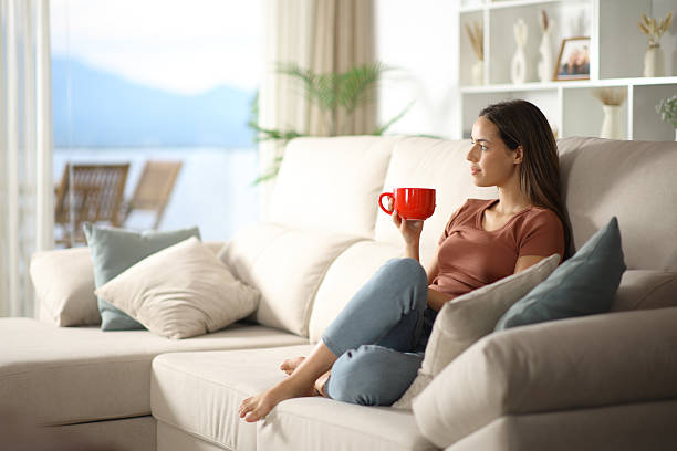 istock Woman relaxing at home holding red coffee mug on a couch 2229042652