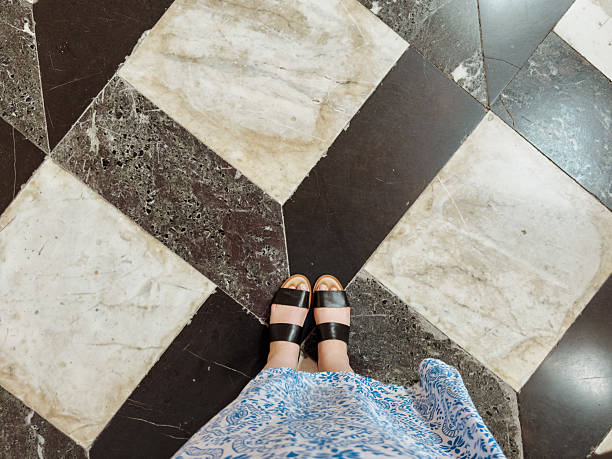 Worn geometric marble floor pattern with black and beige tiles in historical building interior, ancient architecture texture detail