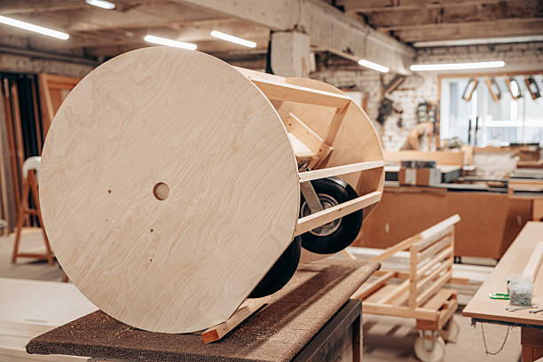 A custom-built wooden structure with large circular plywood wheels and rubber tires, assembled in a well-lit workshop, showcasing creative craftsmanship and design