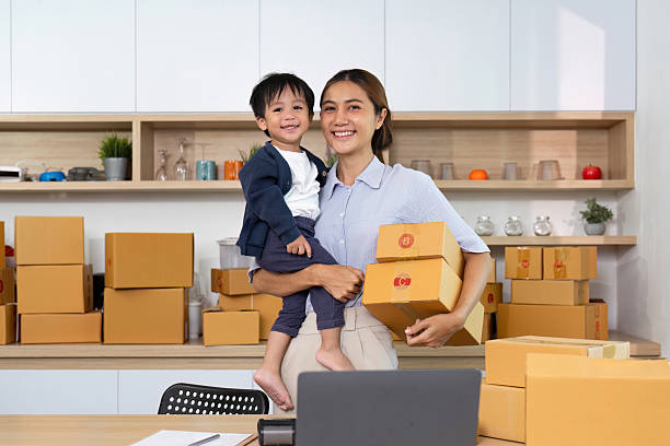 istock Happy mother holding boxes with son in home office 2229047942