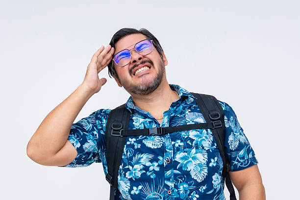 istock Middle-aged man in a Hawaiian shirt gets a headache looking frustrated, realizing he forgot an item at home, isolated on a white background. 2229048320