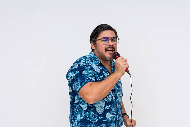 istock A lively middle-aged man sings passionately into a microphone wearing a vibrant Hawaiian shirt, isolated on a white background. 2229048498