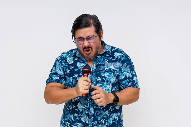 istock A rowdy and possibly drunk middle aged tourist tries to sing a high note into the microphone during a fun karaoke night. Looking cringe. 2229049697