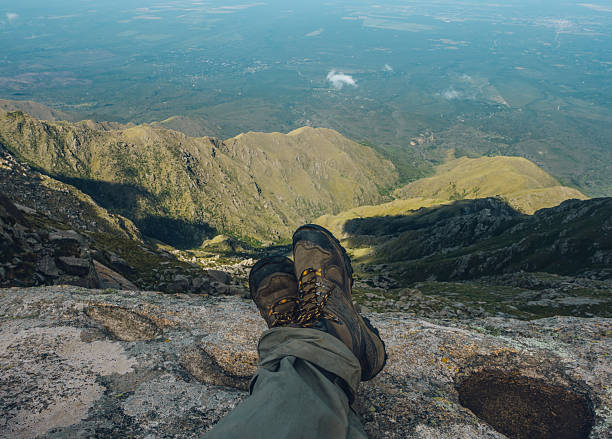 Hiker resting on a mountain top, enjoying the scenic view of a valley below