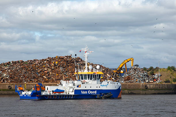 a green trailing suction hopper dredger is rainbowing at the western scheldt sea closeup