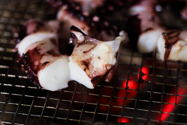 Octopus tentacle cut into small pieces on stainless steel grill