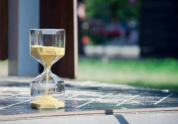 Hourglass with flowing golden sand on wooden table . Space for text