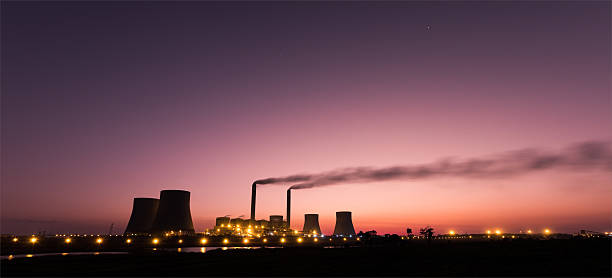 Old-fashioned, coal-fired power station at Kelvin, East of Johannesburg, South Africa, with multiple cooling towers seen against a smoky, cloudy sky with copy space.