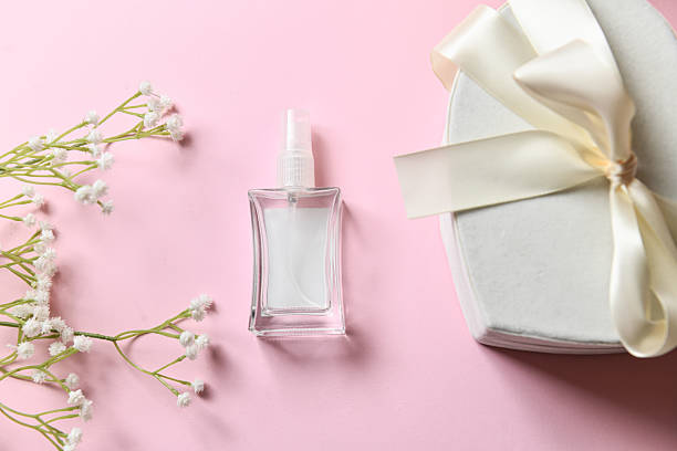 Empty Perfume Bottle And Gift Box Decorated With Simple White Flowers On Pink Background
