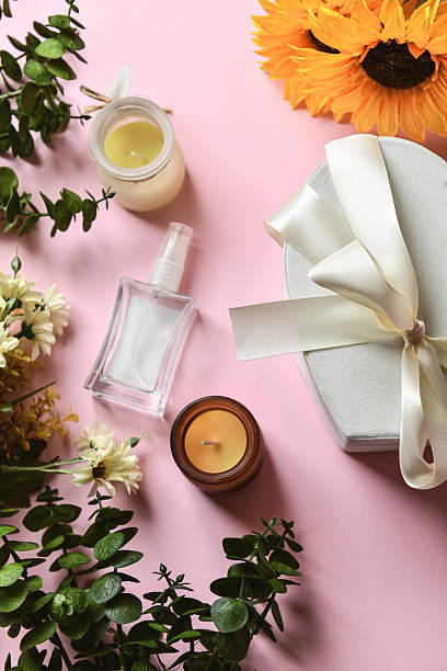 Pink Background Featuring Flowers Framing Gift Box Scented Candles And Spray Bottle