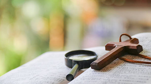 A 65-year-old copy of the King James Version of the Holy Bible is placed on a richly grained Rosewood table. It is open at Psalm 91, the favourite of many believers. Keeping the Bible open at the Psalm, they believe, offers them protection. A bookmark is visible.  The reader's eyeglasses are on the open Bible, indicating that he has taken a break. Indoor studio close-up shot; copy space. No people.