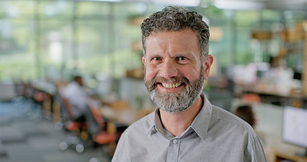 istock Mature Caucasian Businessman Smiling in Modern Open Space Office with Bright Natural Light 2229073884