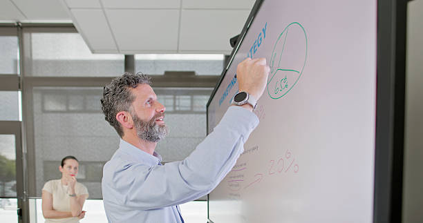 istock Mature Businessman Leading Office Presentation with Diverse Colleagues in Bright Modern Workspace 2229073906
