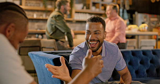 istock Mid Adult Friends Sharing Laughs Over Mobile Phone In Modern Cafe Setting 2229073926