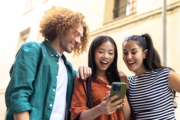 istock Group of happy young students watching funny content on mobile phone 2229076028