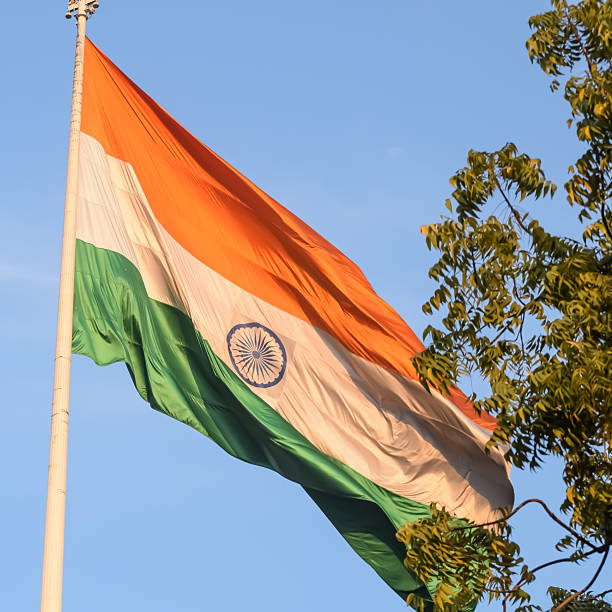 istock India flag flying high at Connaught Place with pride with plain white background, India flag fluttering, Indian Flag on Independence Day and Republic Day of India, tilt up shot, Har Ghar Tiranga 2229079604