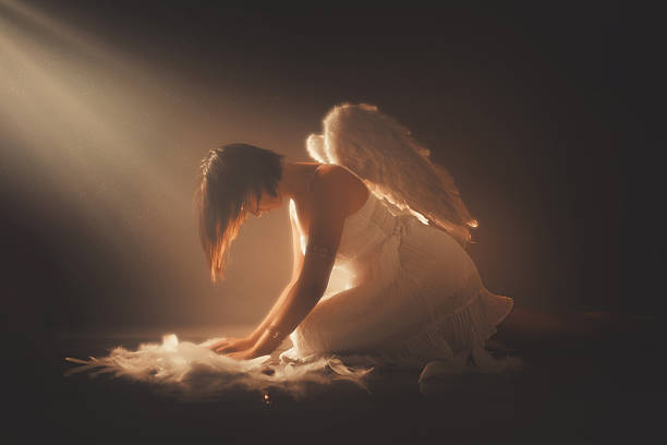 istock Angel Sitting On The Floor While Yellow Light Is Shining Above Her 2229082142