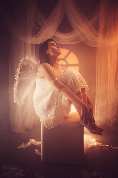 istock Angel Sitting On The Stool Against Yellow Light 2229082473