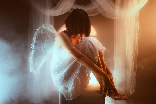 Angel sitting on the stool against yellow light.