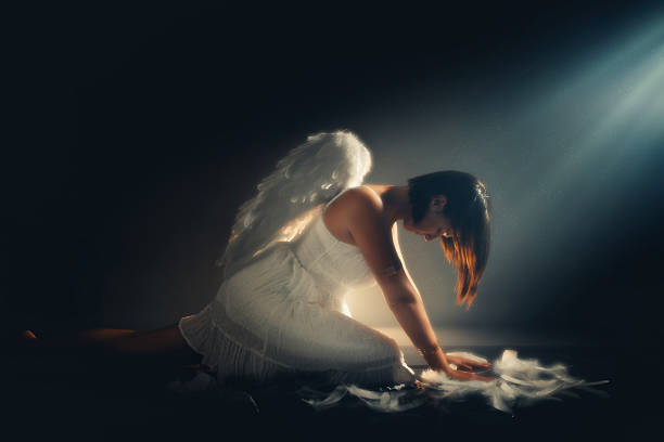Angel sitting on the floor while white light is shinning above her.