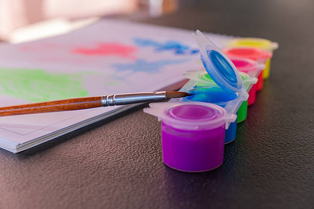 Paintbrush hovering over vivid blue gouache, palette featuring multiple hues for inspiring art studio workspace
