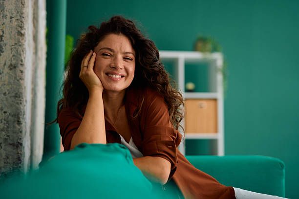 istock Happy woman relaxing on sofa at home, smiling and looking at camera 2229088367